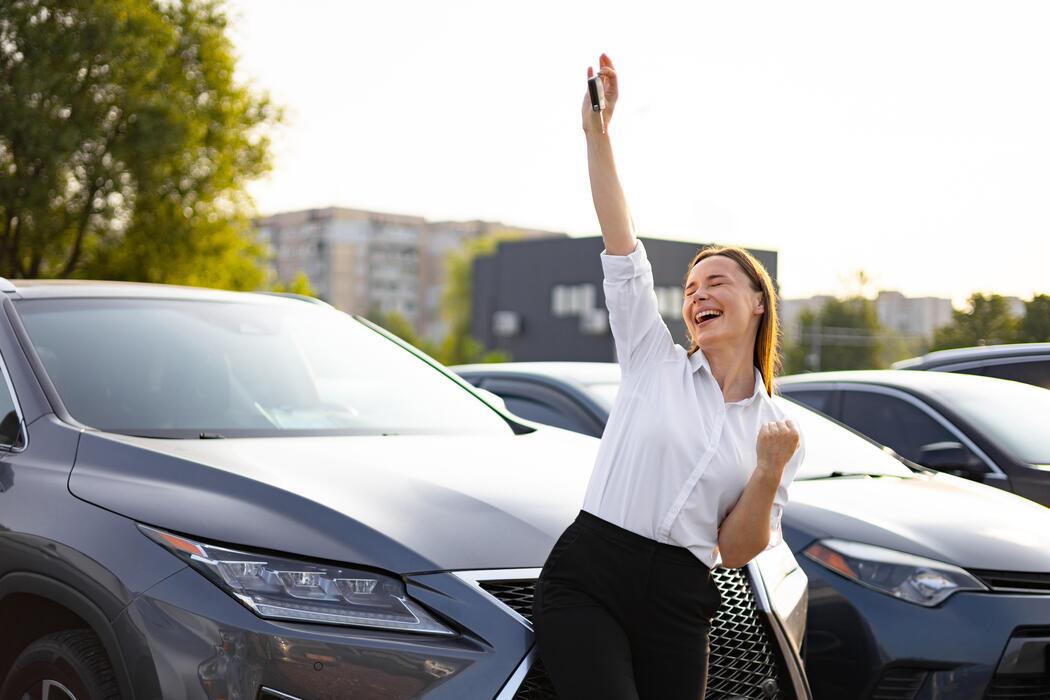 a-joyful-woman-celebrates-buying-a-new-car-holding-up-the-keys-with-elation-at-the-dealership-photo